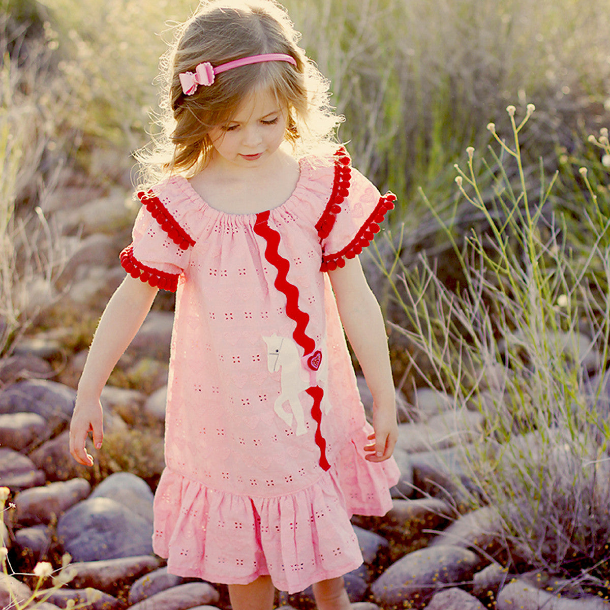 Blonde haired girl in a pink and red dress | Featured image for the Girls Dress Patterns Page for Treasurie.