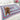 Dog sitting on a colorful crocheted granny stitch rectangle blanket in a bedroom setting.