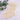 Crocheted white stocking with a bow on a light background with greenery.
