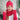 Woman wearing a pink lace crochet beanie, scarf, and gloves set indoors.